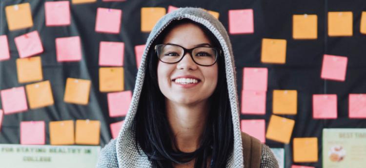 girl smiling and wearing glasses and a hoodie