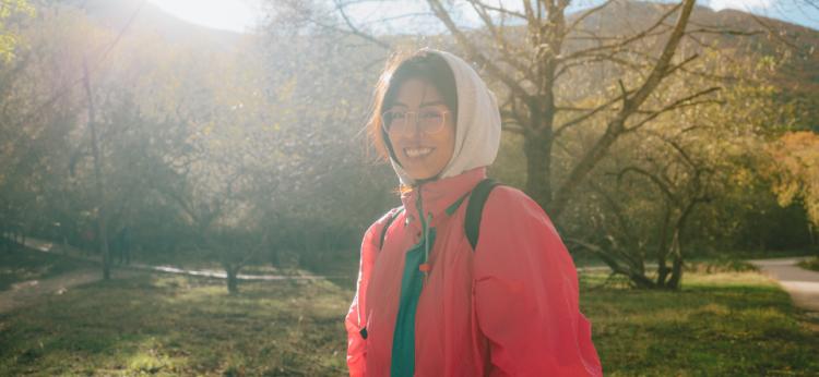 A woman dressed in a colorful raincoat, hikes in a cold autumn day.