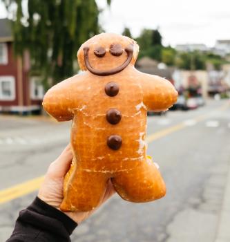 UGC POV of a woman holding a holiday gingerbread man donut while traveling through the town of Pouslbo, Washington.