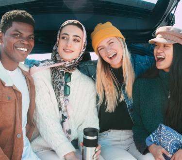 Gen Z friends and lesbian couple in the back of a car during a roadtrip by the beach
