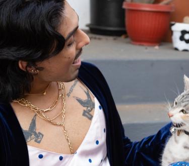 Happy stylish latino queer person looking comfortable on porch steps